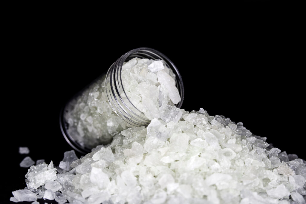 A clear bottle of MDMA that looks like small white rocks.