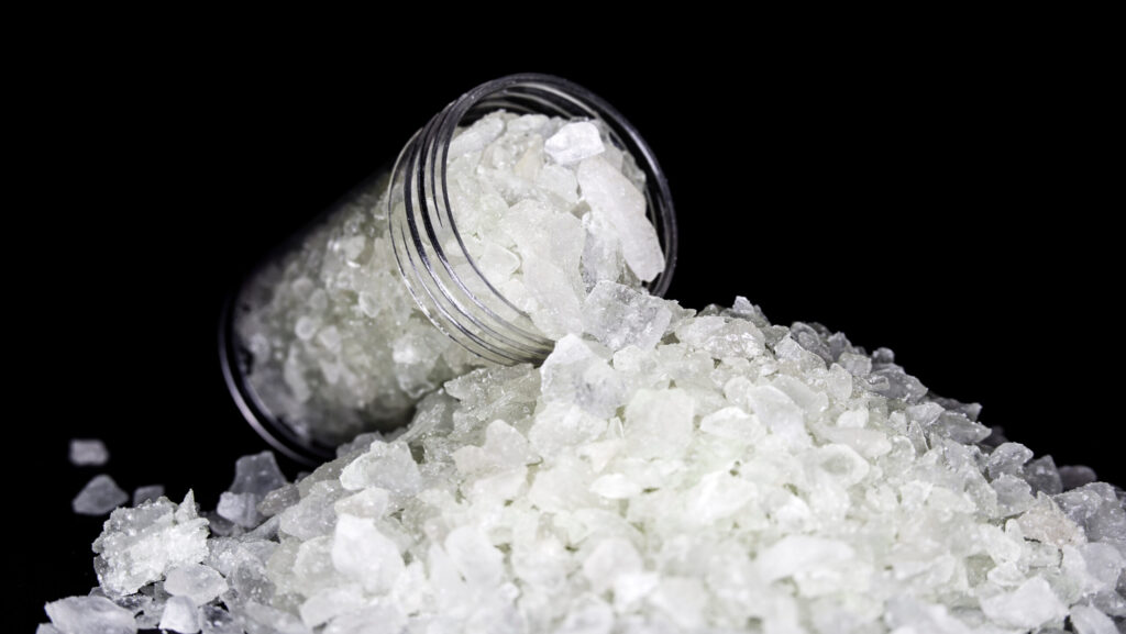 A clear bottle of MDMA that looks like small white rocks.