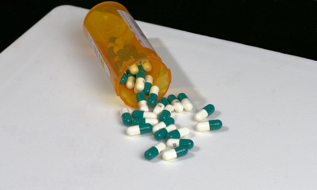 A pharmacy bottle is spilled over with green and white pills of temazepam for withdrawal.