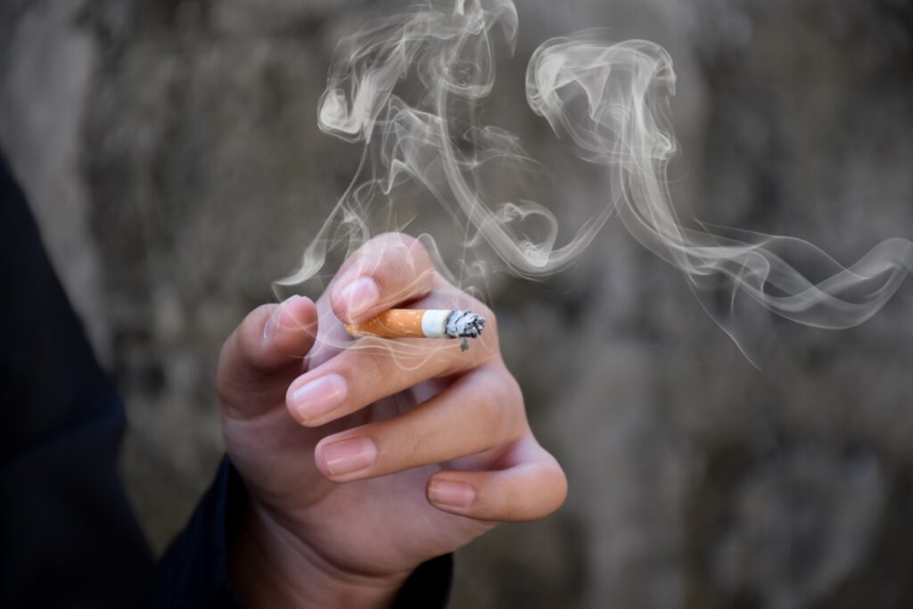 A man's hands holding a sherm stick drug, which is a cigarette dipped in PCP or embalming fluid.
