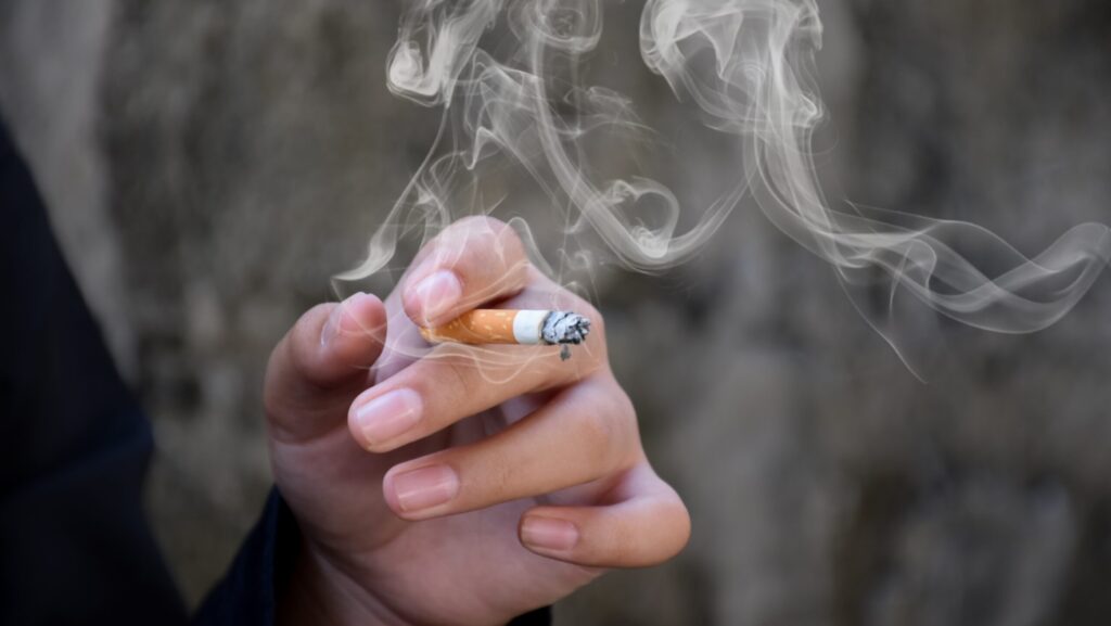 A man's hands holding a sherm stick drug, which is a cigarette dipped in PCP or embalming fluid.