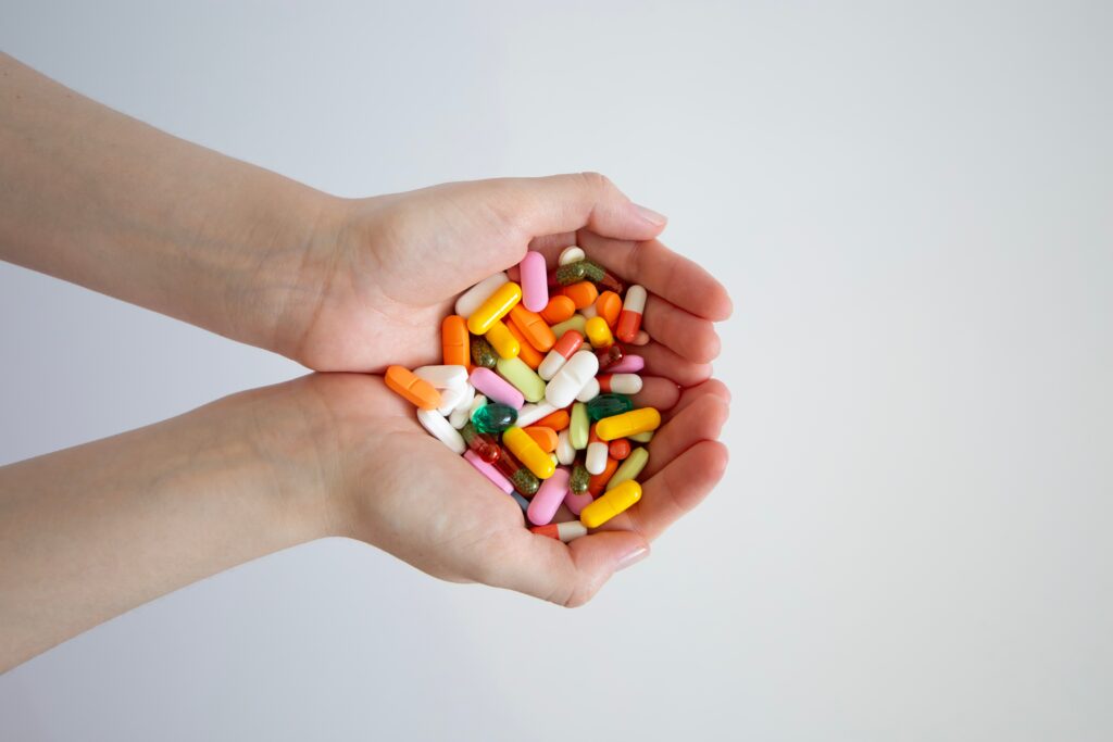 A person with a handful of colorful pills represents signs someone is addicted to pain pills.