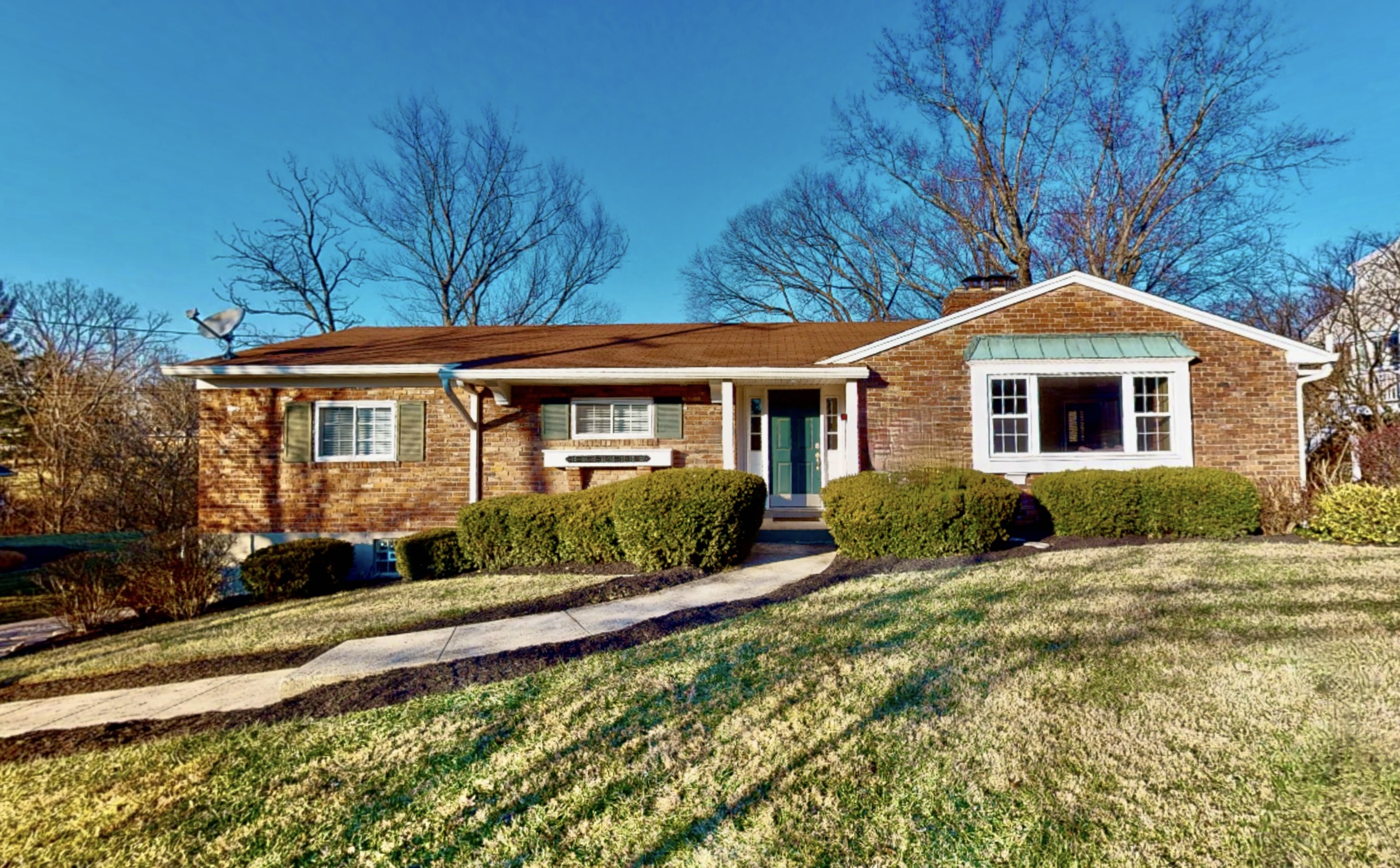House with warm bricks, nice green, cut grass, blue skies in residential neighborhood