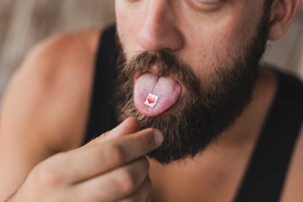 A man with an LSD paper on his tongue questioning if he can overdose on LSD.
