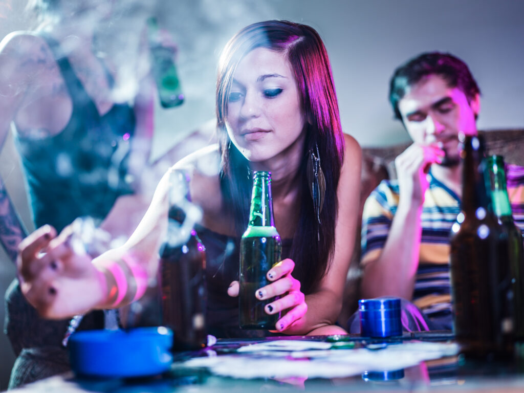 A young women and her friends drinking and smoking represents why people start using drugs.