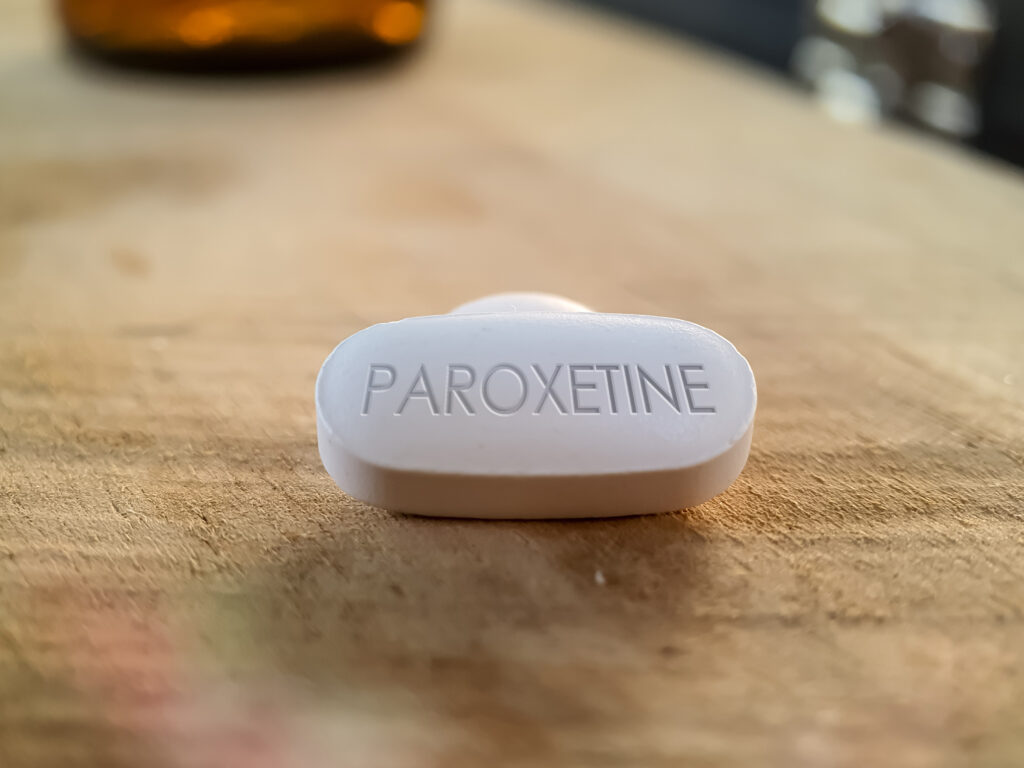 A paroxetine pill on a wooden table represents Paxil withdrawal symptoms.