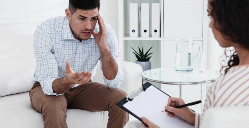 A man talking to a female addiction counselor after searching for alcohol therapist near me.
