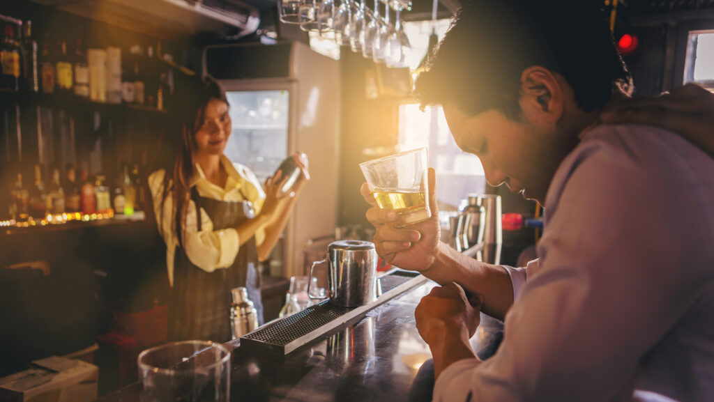 A female bartender is serving a man at a bar drinking and going on a 3 day bender.