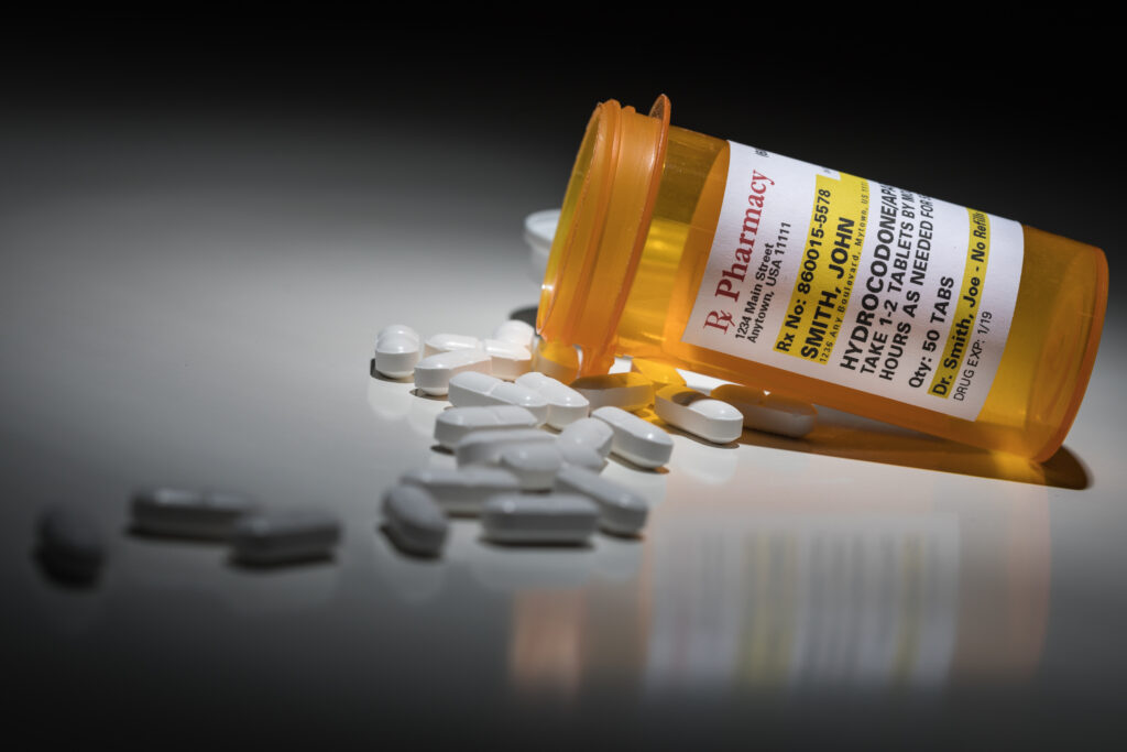A pharmacy bottle of hydrocodone spilled onto a table representing how easy it is for vicodin addiction to start.