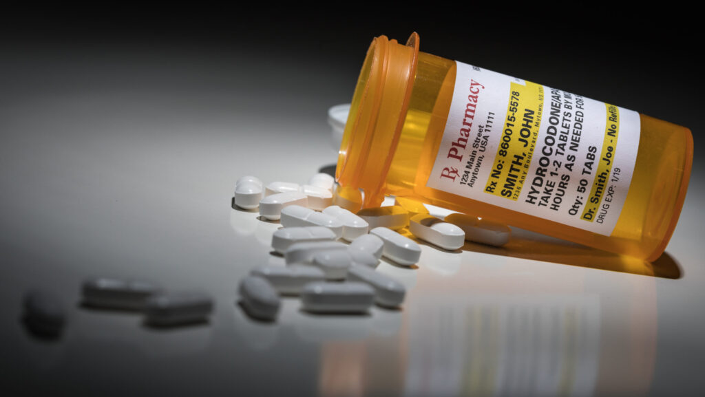 A pharmacy bottle of hydrocodone spilled onto a table representing how easy it is for vicodin addiction to start.