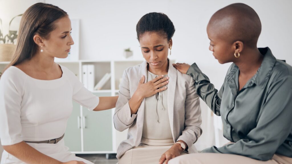 Two females console another women in group therapy session in a residential rehab for women.