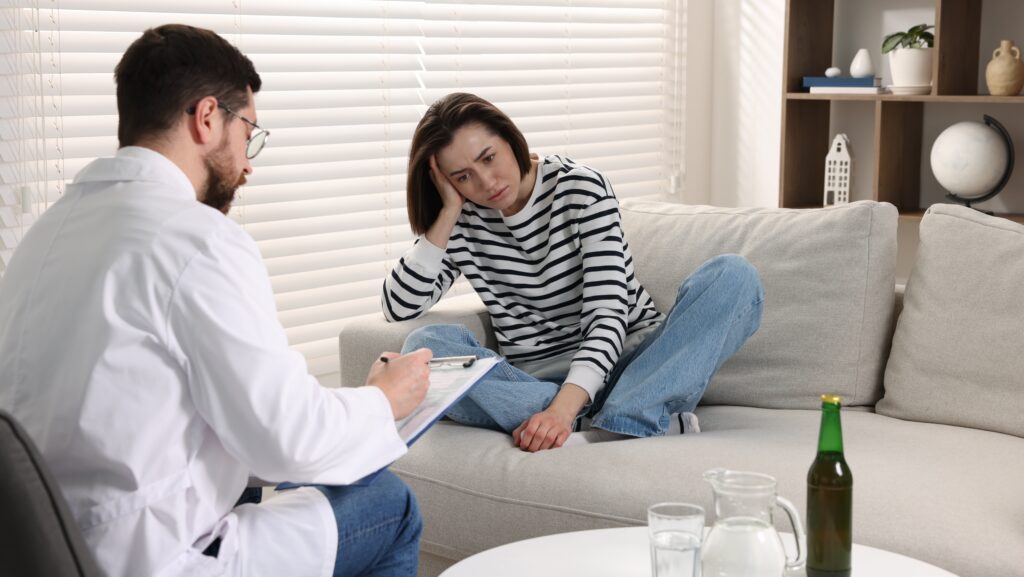 A woman in residential treatment talking to her male rehab doctor about treatment plan for alcoholism.