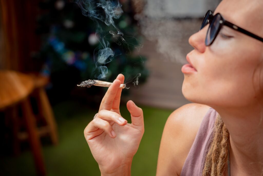 A young woman in glasses holding and smoking a joint wonders is smoking a joint a day considered a heavy user.
