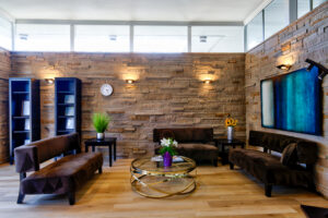 Brick stone walls with bright lighting shines on 3 modern couches with TV on one wall