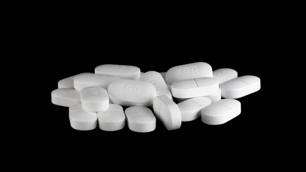 White pills of 100mg of Zoloft on a black background.