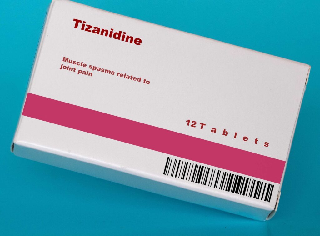 A pharmacuetical box of Tizanidine on a blue background. The muscle relaxant medication is not a narcotic and doesn't have a black box label.