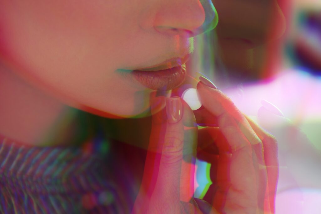A young woman taking a hallucinogenic pill represents the innovative finding in psychedelic treatment for depression.