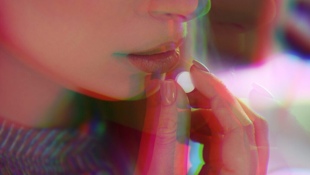A young woman taking a hallucinogenic pill represents the innovative finding in psychedelic treatment for depression.