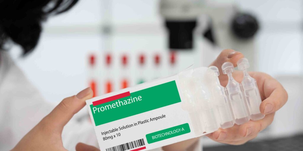A woman holding pharmacy prescription box explaining how promethazine works.