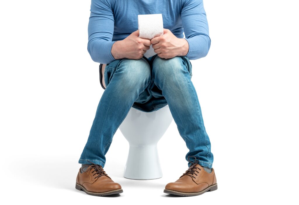 A man sitting on the toilet after taking his medication wondering does Adderall make you poop?