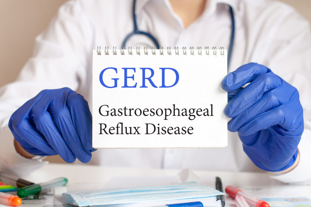 A doctor holding up a notecard that says GERD and reflects the relationship between alcohol and GERD.