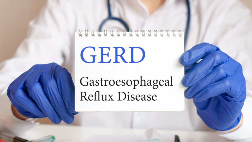 A doctor holding up a notecard that says GERD and reflects the relationship between alcohol and GERD.
