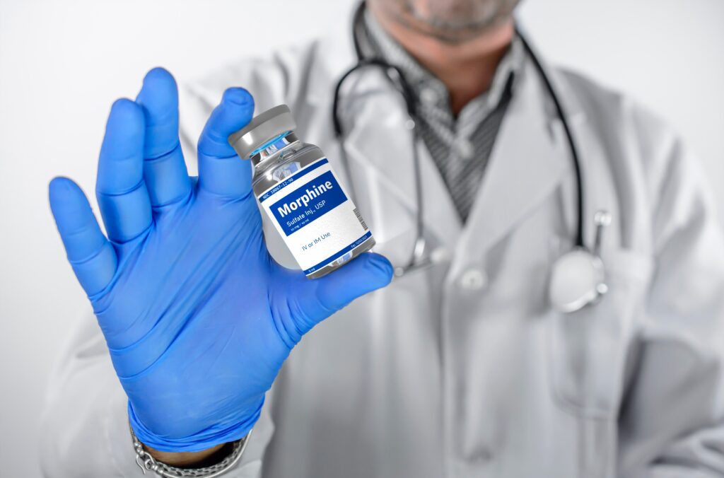 A male clinician holding up a liquid bottle of morphine represents signs of morphine abuse.