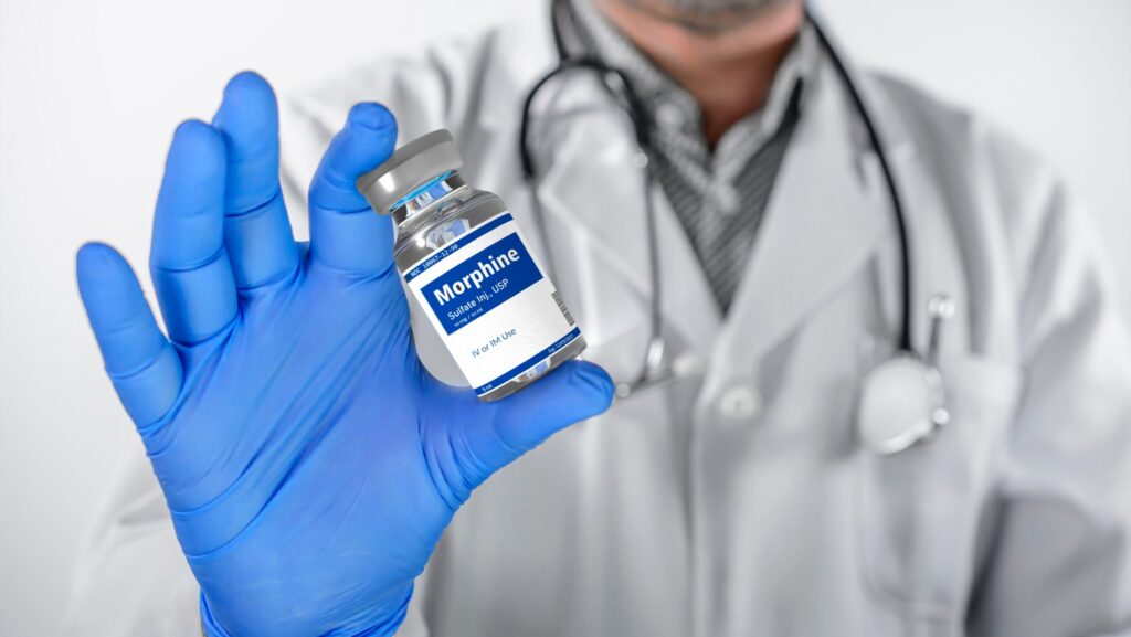 A male clinician holding up a liquid bottle of morphine represents signs of morphine abuse.