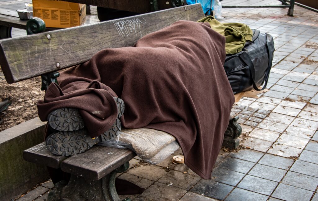 A homeless person laying on a bench begs the question of what percentage of homeless people are drug addicts.