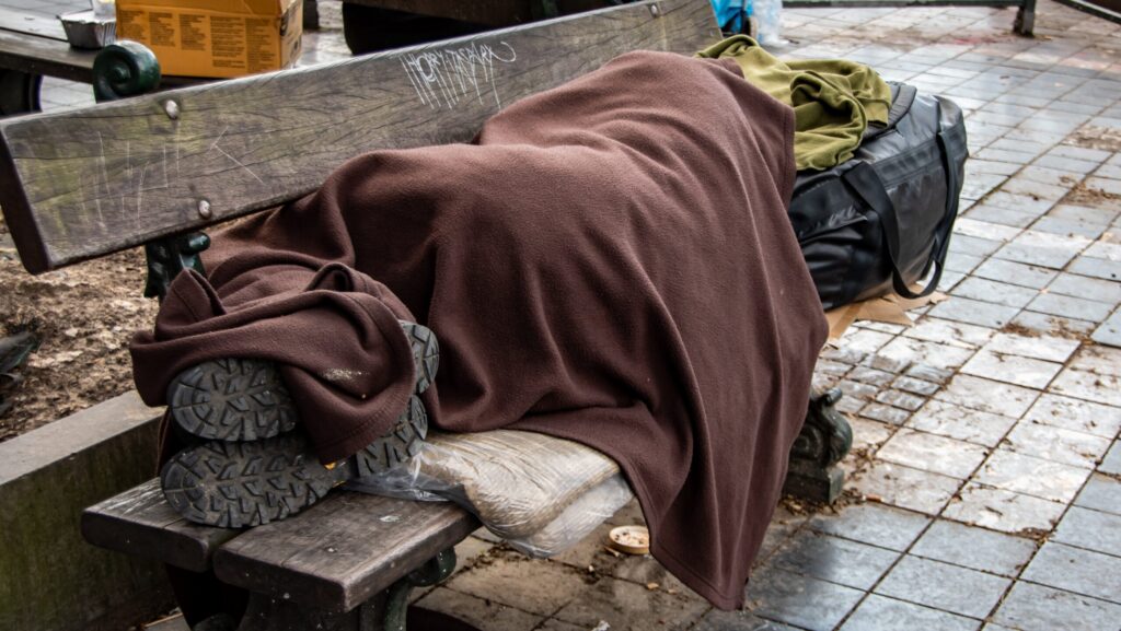 A homeless person laying on a bench begs the question of what percentage of homeless people are drug addicts.