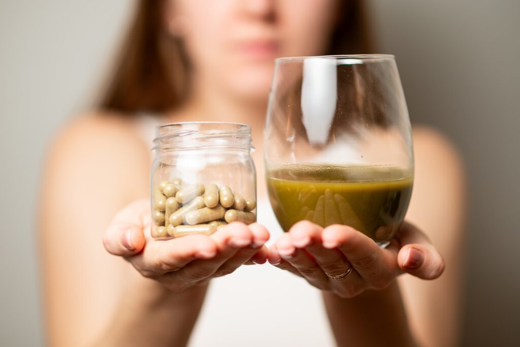 A woman holding a glass jar of kraotm pills and cup of kratom tea and looking for kratom addiction help.