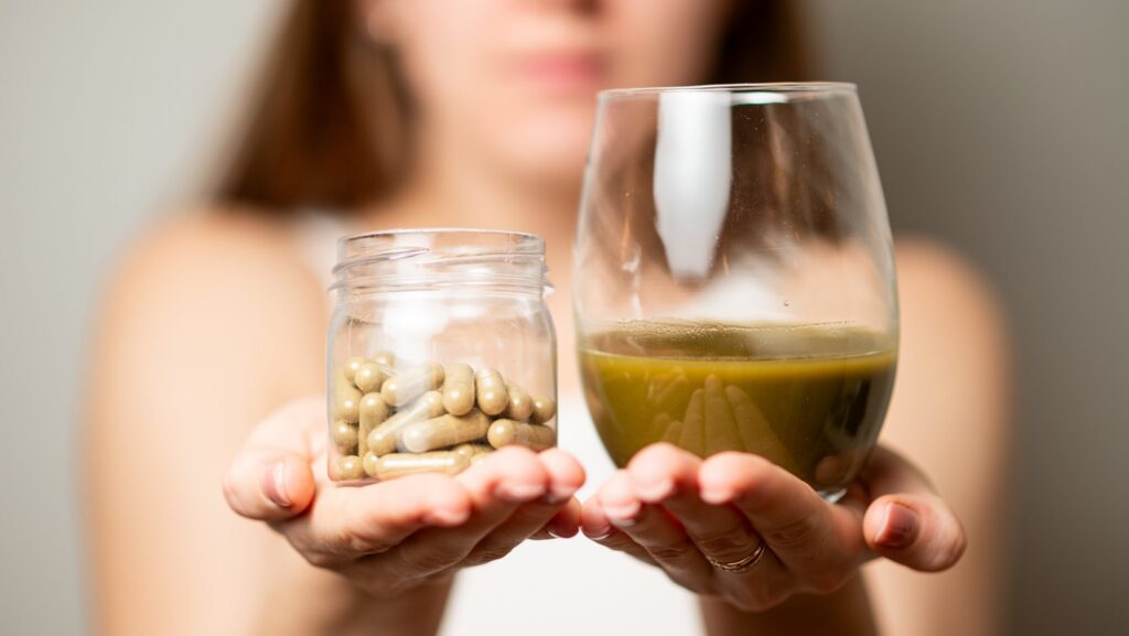 A woman holding a glass jar of kraotm pills and cup of kratom tea and looking for kratom addiction help.
