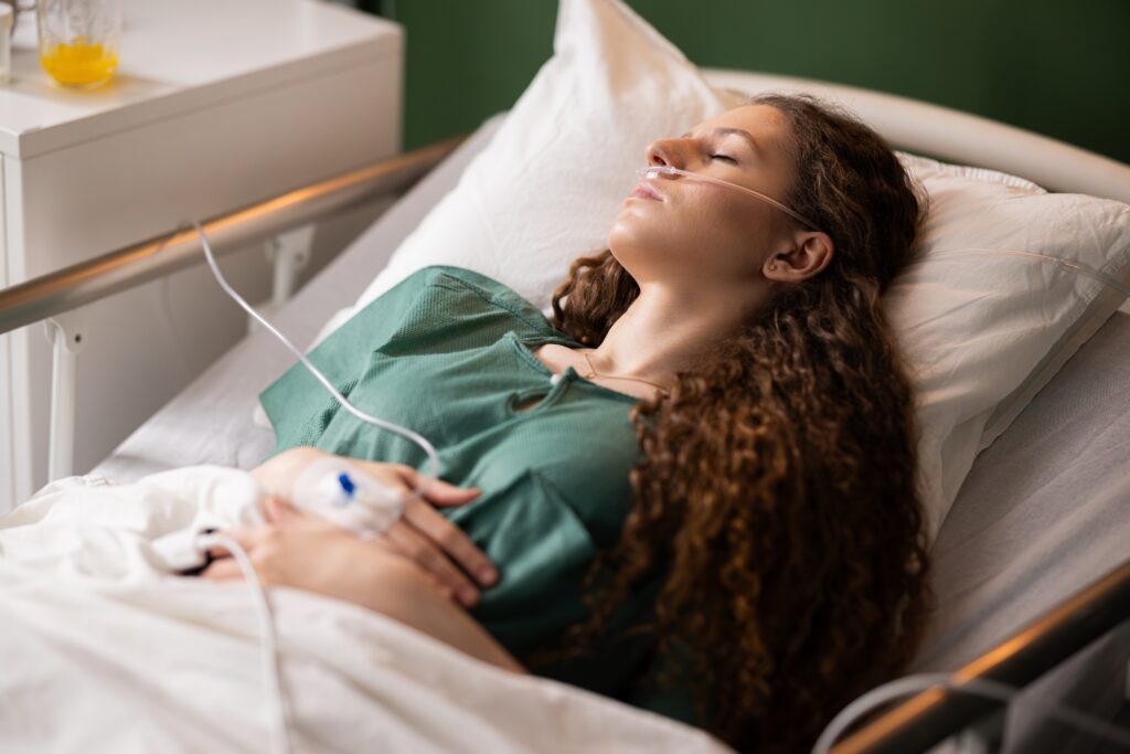 A woman lying in a hospital bed who just finished getting her stomach pumped due to acute alcohol intoxication.