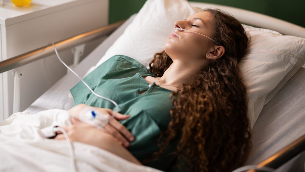 A woman lying in a hospital bed who just finished getting her stomach pumped due to acute alcohol intoxication.