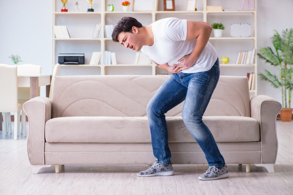 A man bent over holding his stomach because he is experiencing alcohol effects on the pancreas.