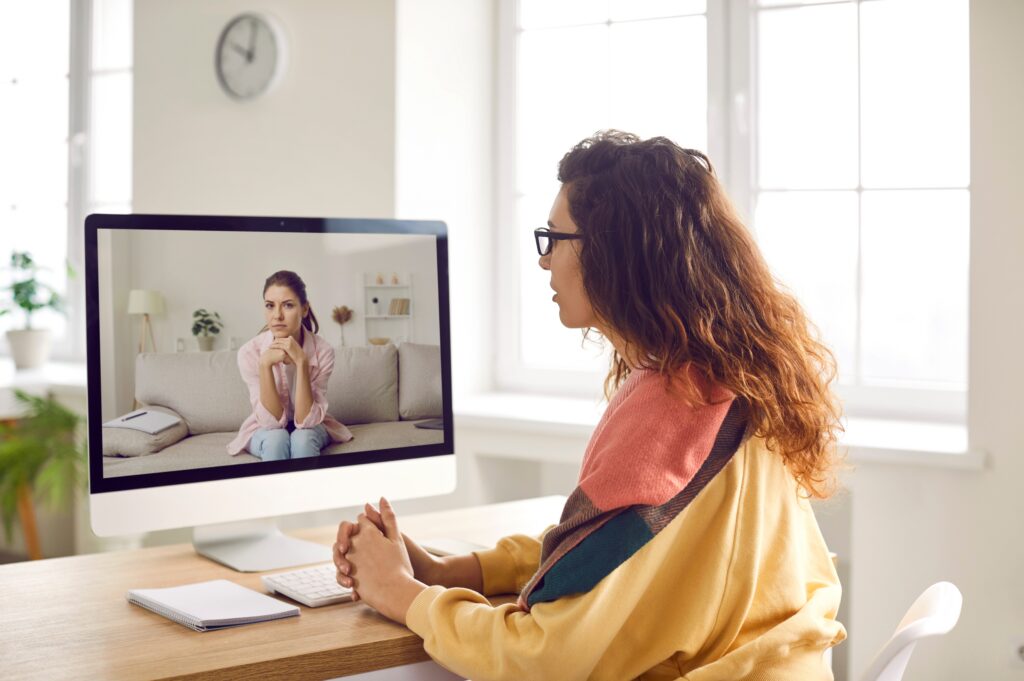 A young woman engaging in virtual intensive outpatient therapy through video conferencing.