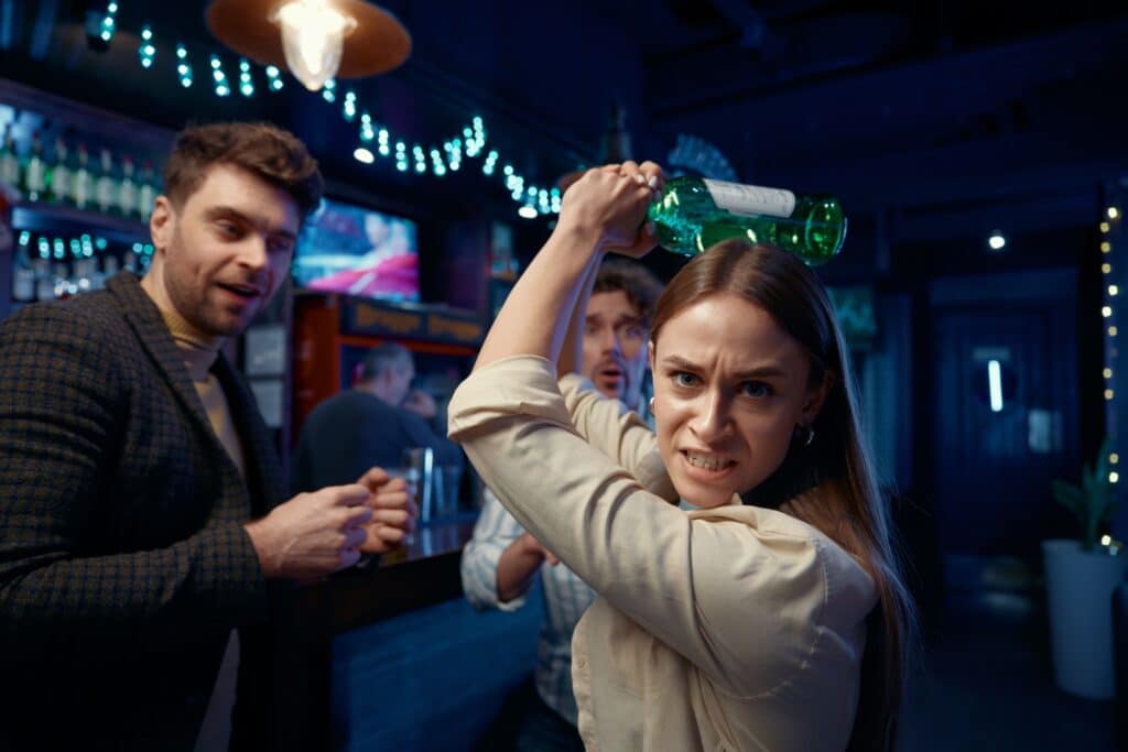 A woman who becomes angry drunk when consuming alcohol holds a bottle about to strike someone.