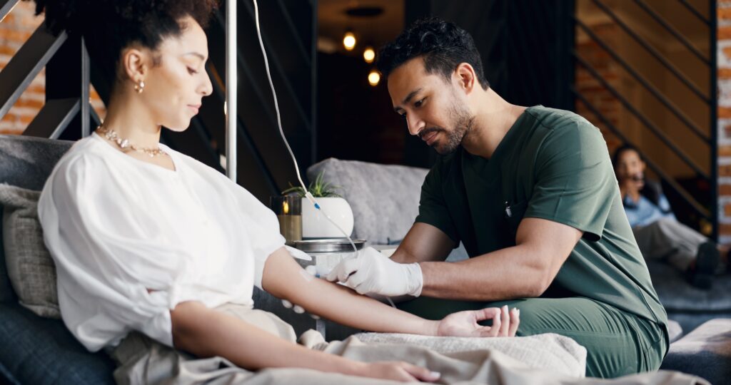 A young woman in medically supervised detox with a male nurse helping her with an IV.