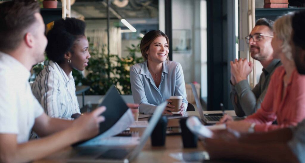 A group of people in a work meeting with a young women who is a functional addict, leading the discussion.