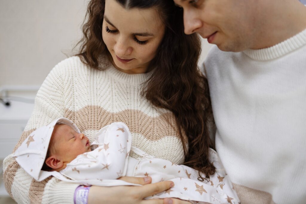 A young couple holding their newborn baby wondering what's neonatal abstinence syndrome and if their child is affected.